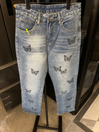 Light blue denim pants with black butterfly embroidery on legs and waistband
