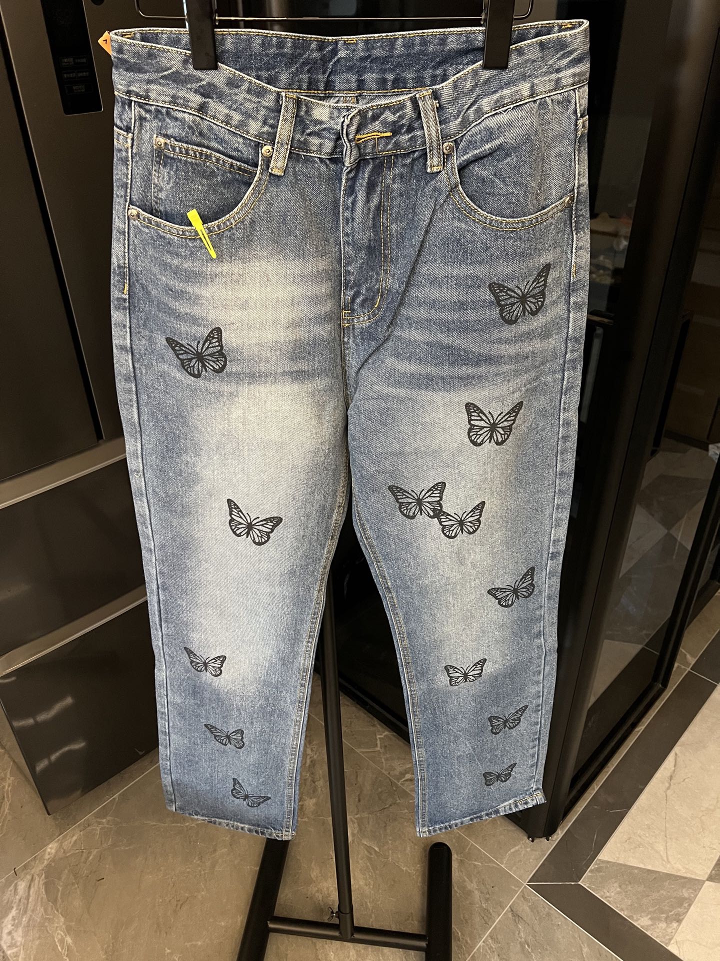 Light blue denim pants with black butterfly embroidery on legs and waistband