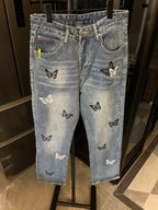 Light wash denim jeans with black and pale butterfly patches, front view
