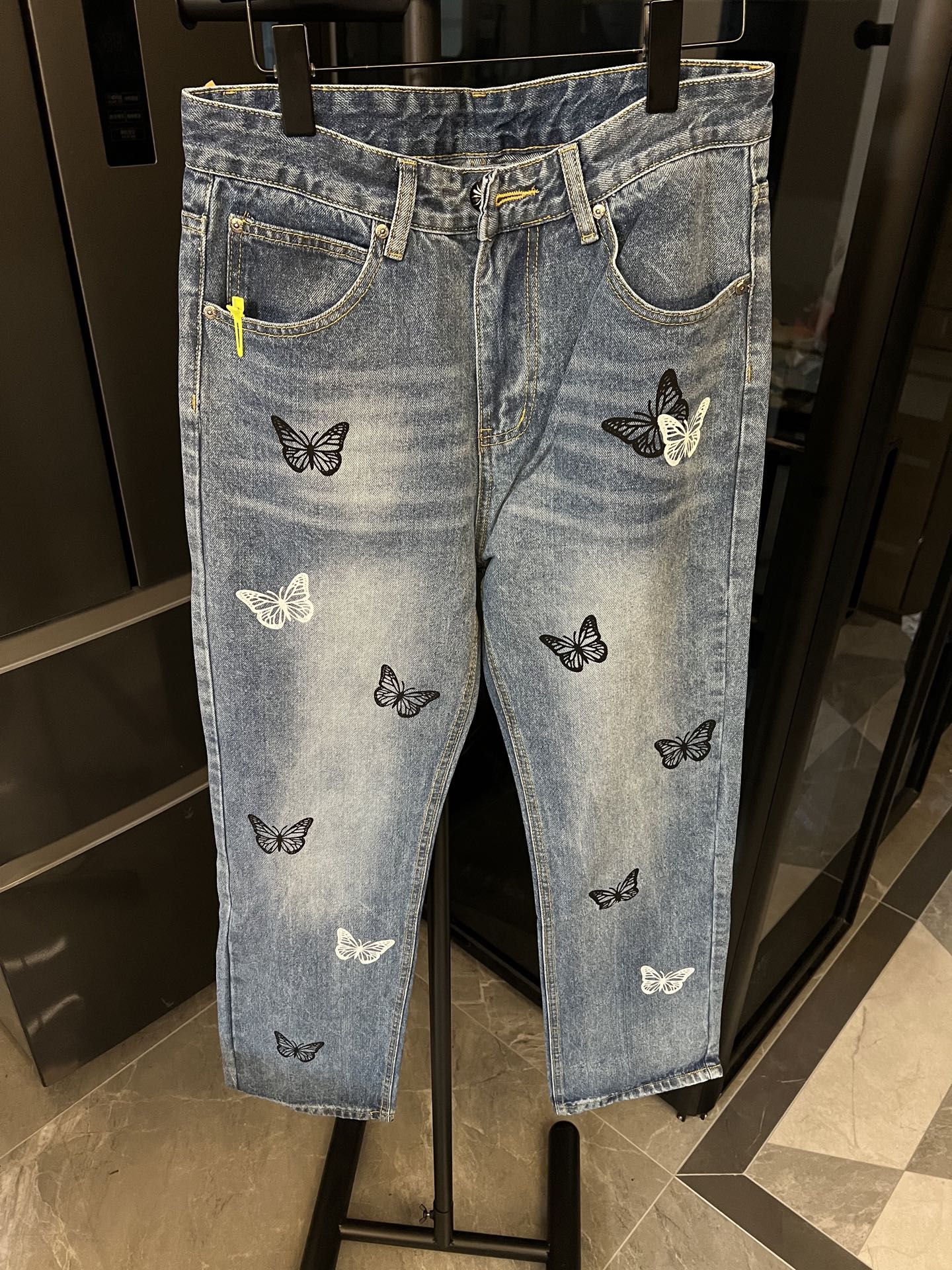 Light wash denim jeans with black and pale butterfly patches, front view