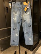 Light wash denim jeans with butterfly patches on the legs, front view on hanger