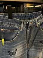 Light wash denim jeans with butterfly patch, close view of front waistband and fly