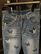 Light wash denim jeans with butterfly patches, waistband and pockets visible