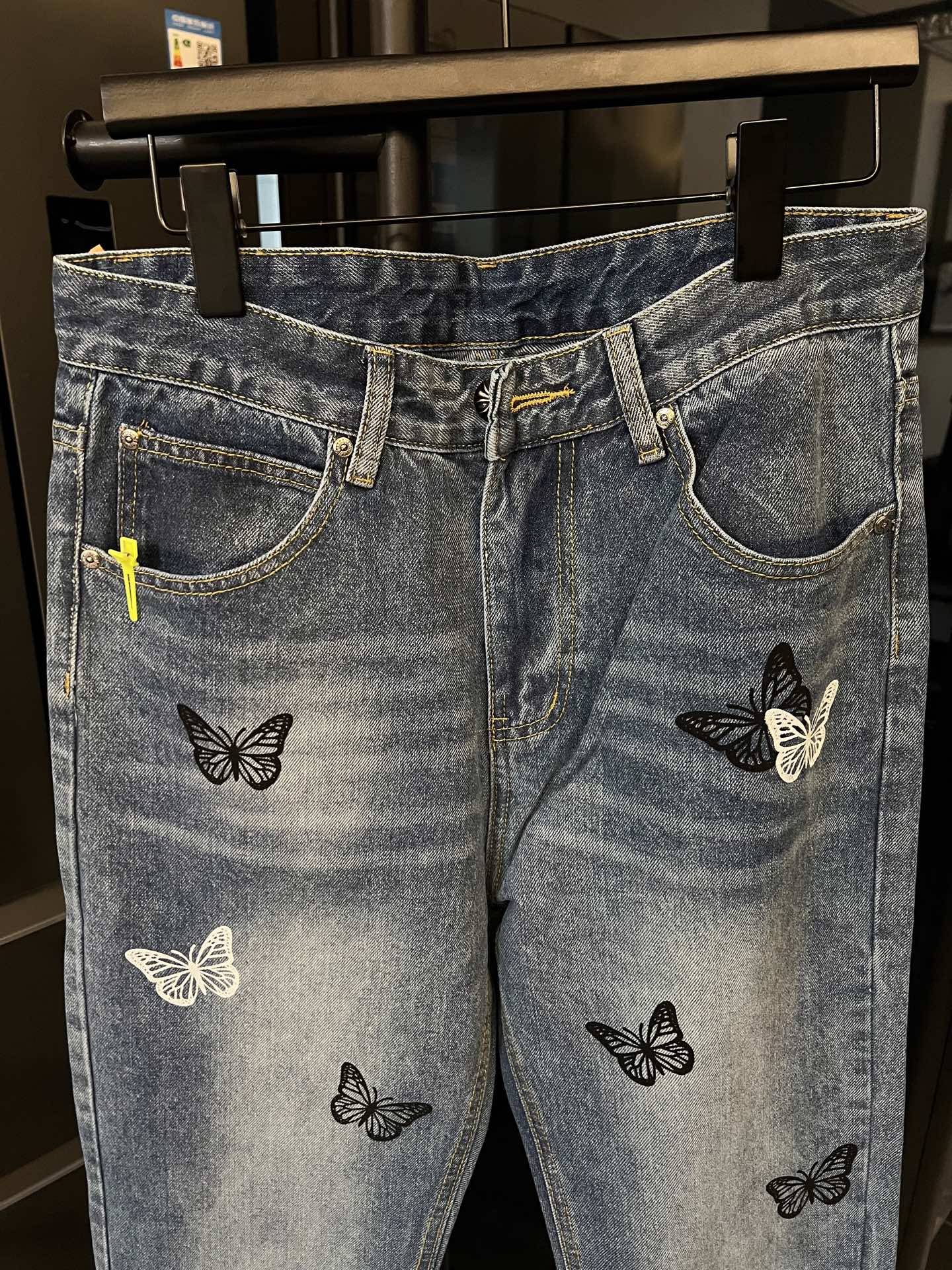Light wash denim jeans with butterfly patches, waistband and pockets visible