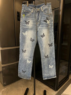 Light wash denim jeans with black and white butterfly patches, straight front view