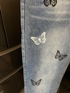 Light wash denim jeans with butterfly patches, close-up of one leg