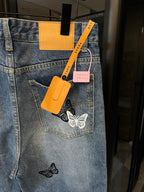 Light wash denim jeans with butterfly patches, back pocket and hanging tags visible