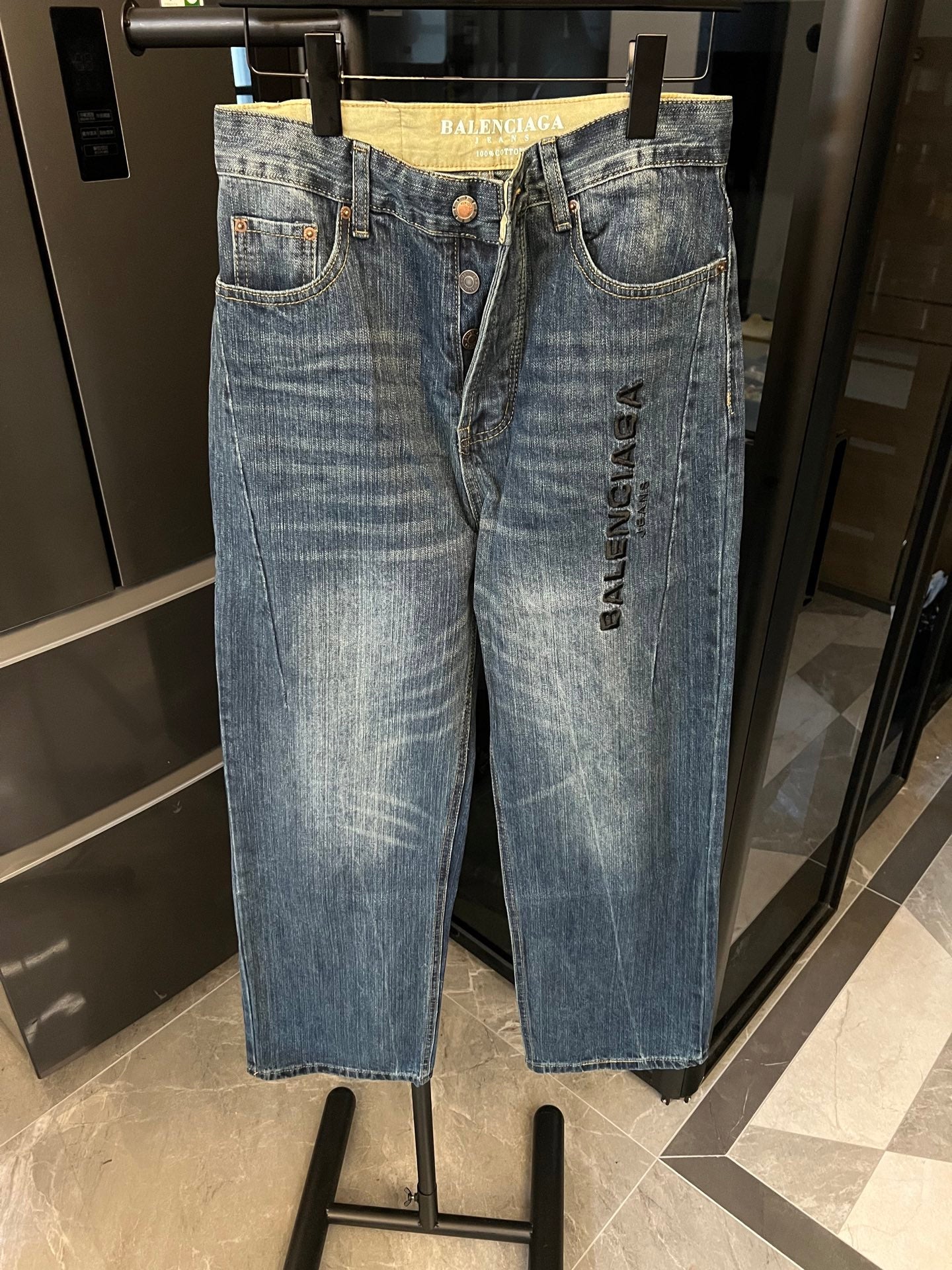 Denim jeans, light blue distressed wash, high-rise waistband, button closure, embroidered logo