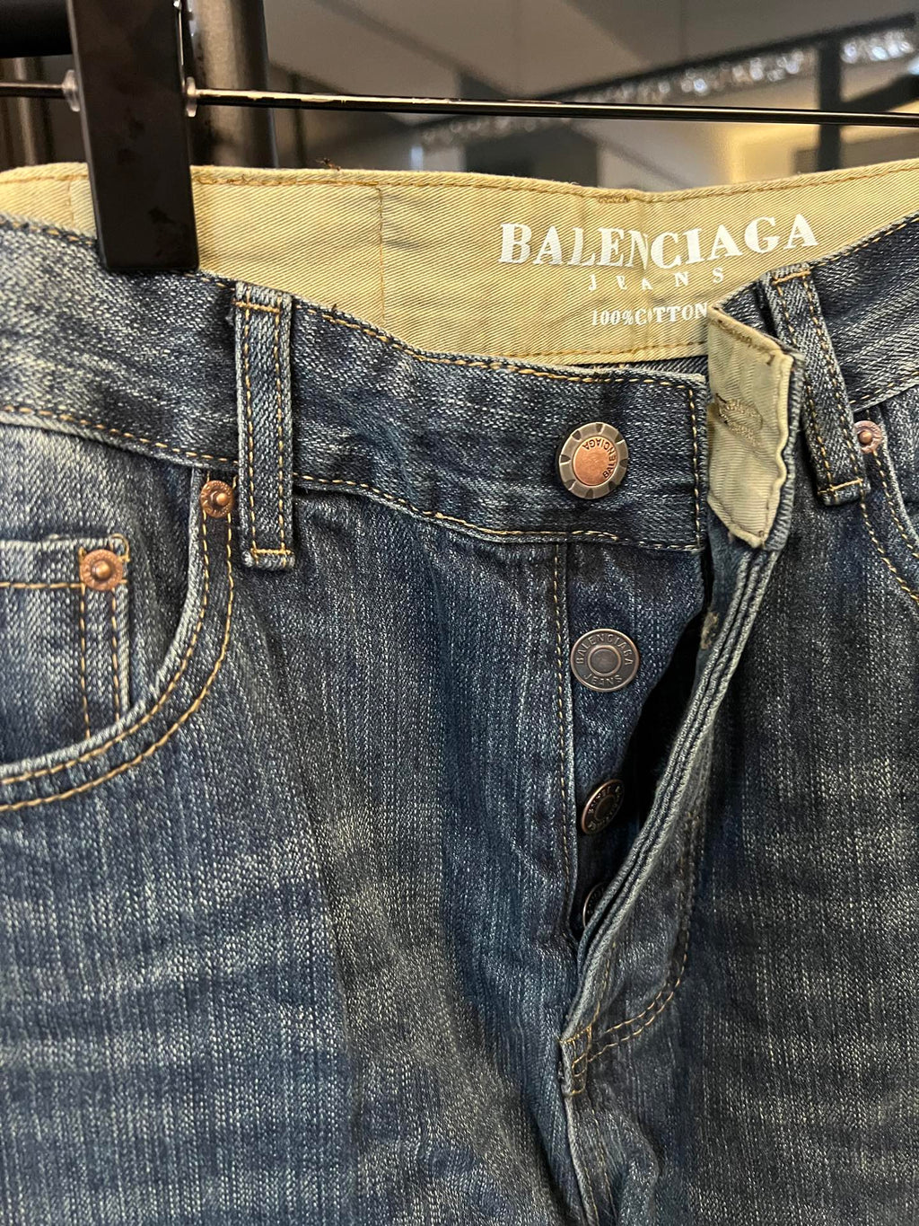 Denim jeans close-up, blue denim waistband with Balenciaga Jeans label and button details
