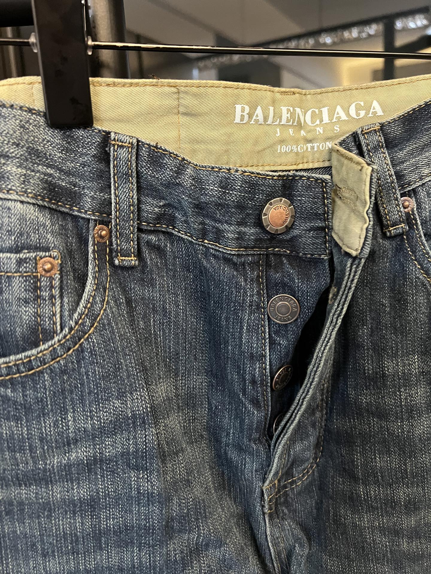 Denim jeans close-up, blue denim waistband with Balenciaga Jeans label and button details