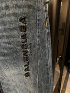 Denim jeans close-up, vertical black logo embroidery on light blue leg seam