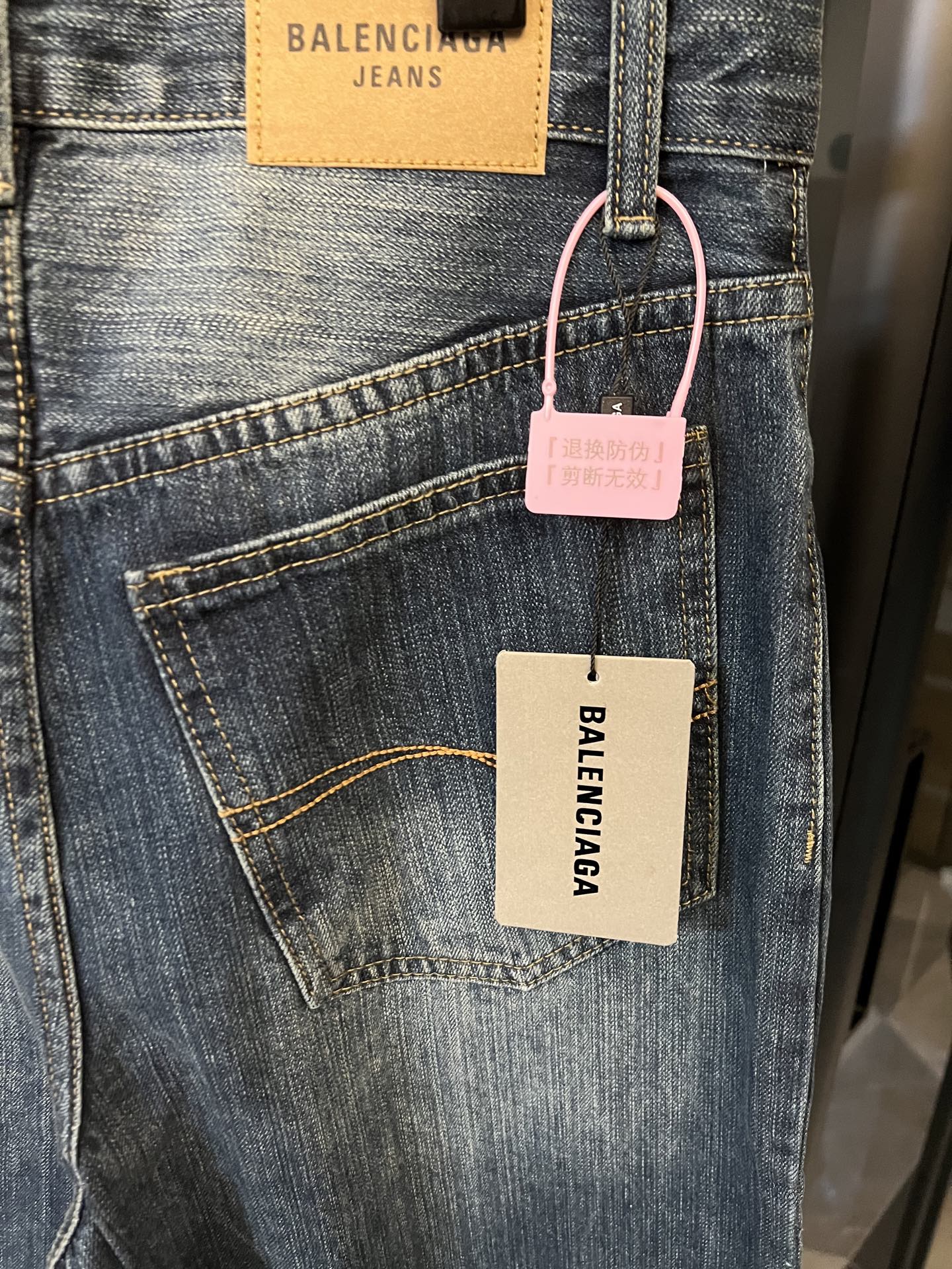 Denim jeans with front pockets, light blue wash, hanging tags on waistband