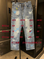Light blue denim pants with butterfly patches and front zipper, shown on display rack