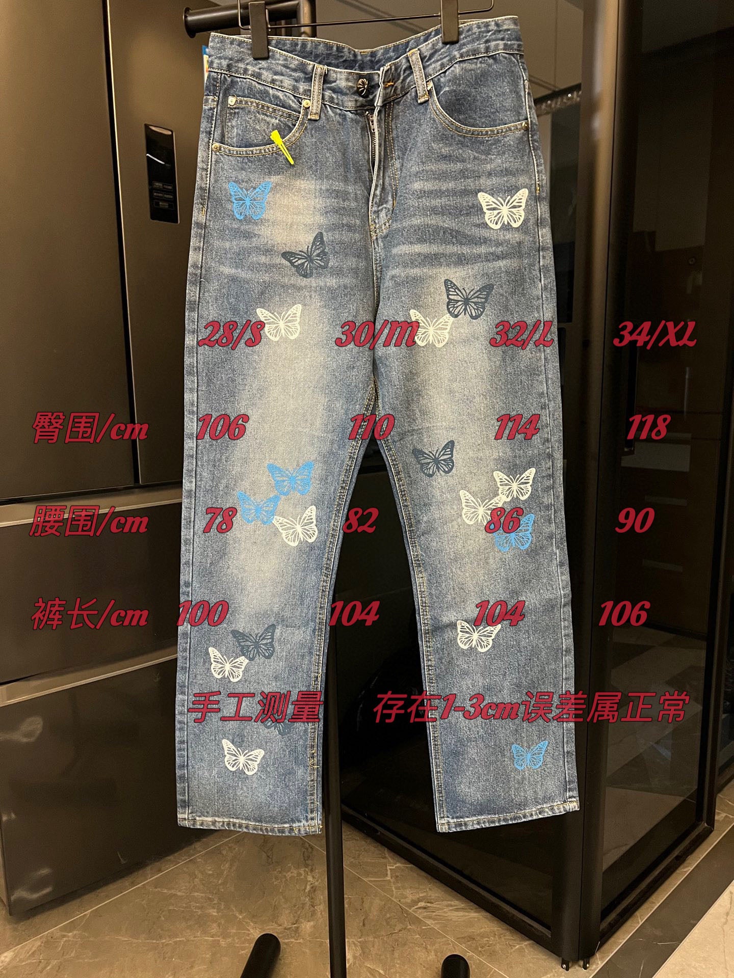 Light blue denim pants with butterfly patches and front zipper, shown on display rack
