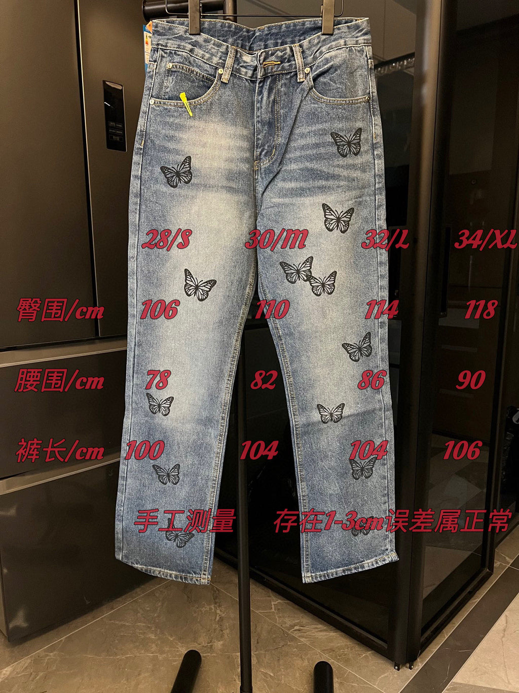 Light blue denim jeans with black butterfly embroidery and red size markings over the front