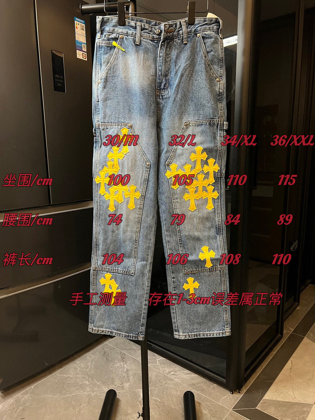 Light blue denim pants with yellow cross embroidery and size chart overlay