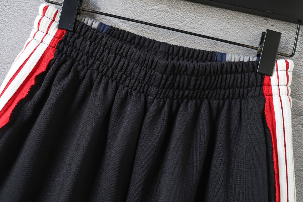 Black Balenciaga track shorts with red/white stripe trim and ruched waistband