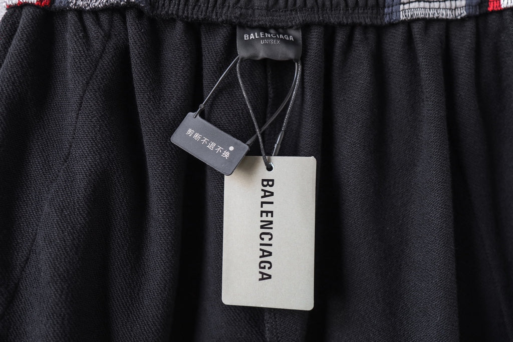Black track pants with elastic waistband and hanging Balenciaga product tags