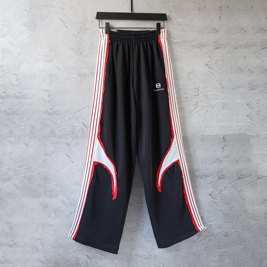 Black track pants with red and white side stripes, wide leg and elastic waistband