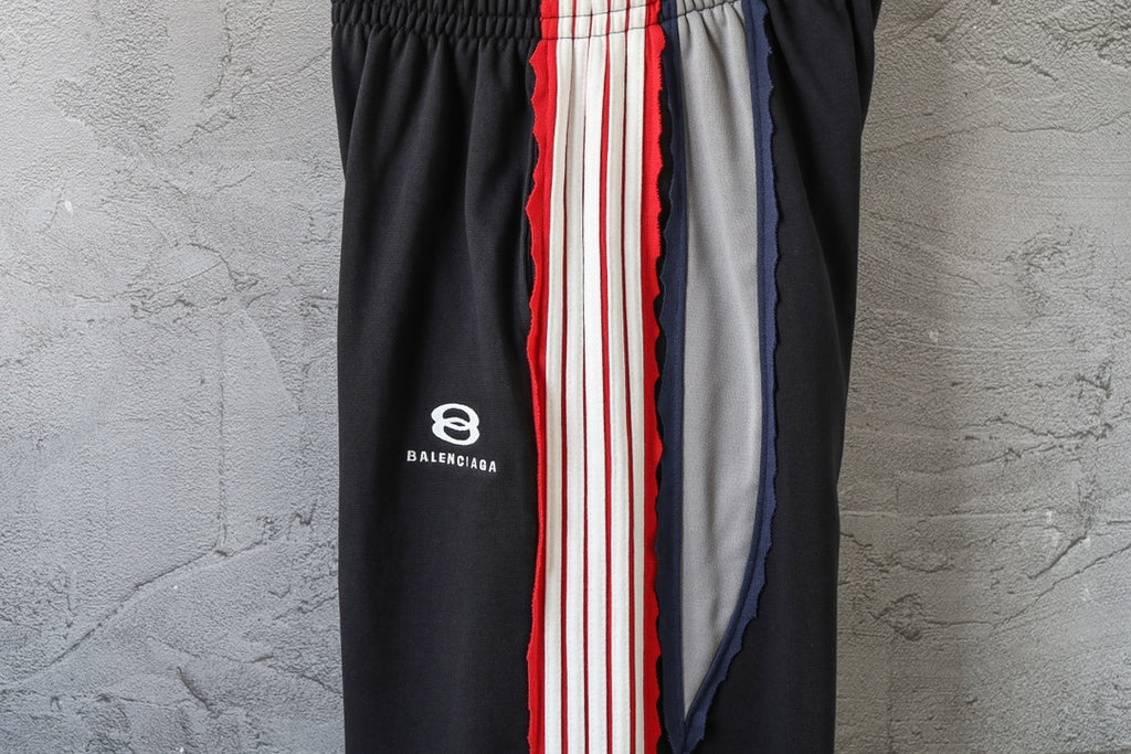 Black track pants with Balenciaga logo and red/white stripe side panel