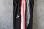 Black track pants with Balenciaga logo and red/white stripe side panel