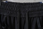 Black track pants waistband with elastic, textured fabric and stitched pleats