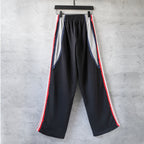Black wide-leg track pants with red and white side stripes and gathered front