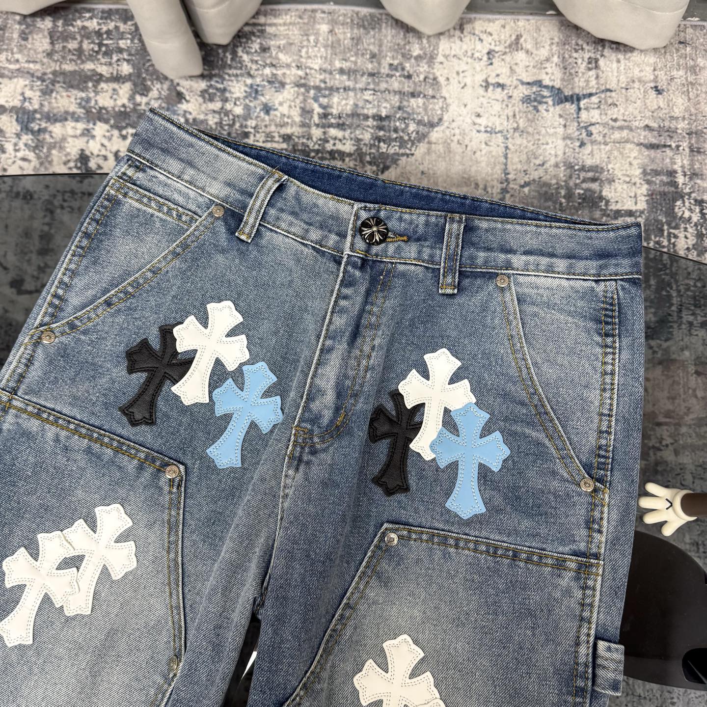 Light blue denim pants with cross applique patches and metal button waistband