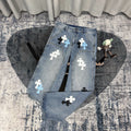 Light blue denim pants with white, black, and light-blue cross appliques