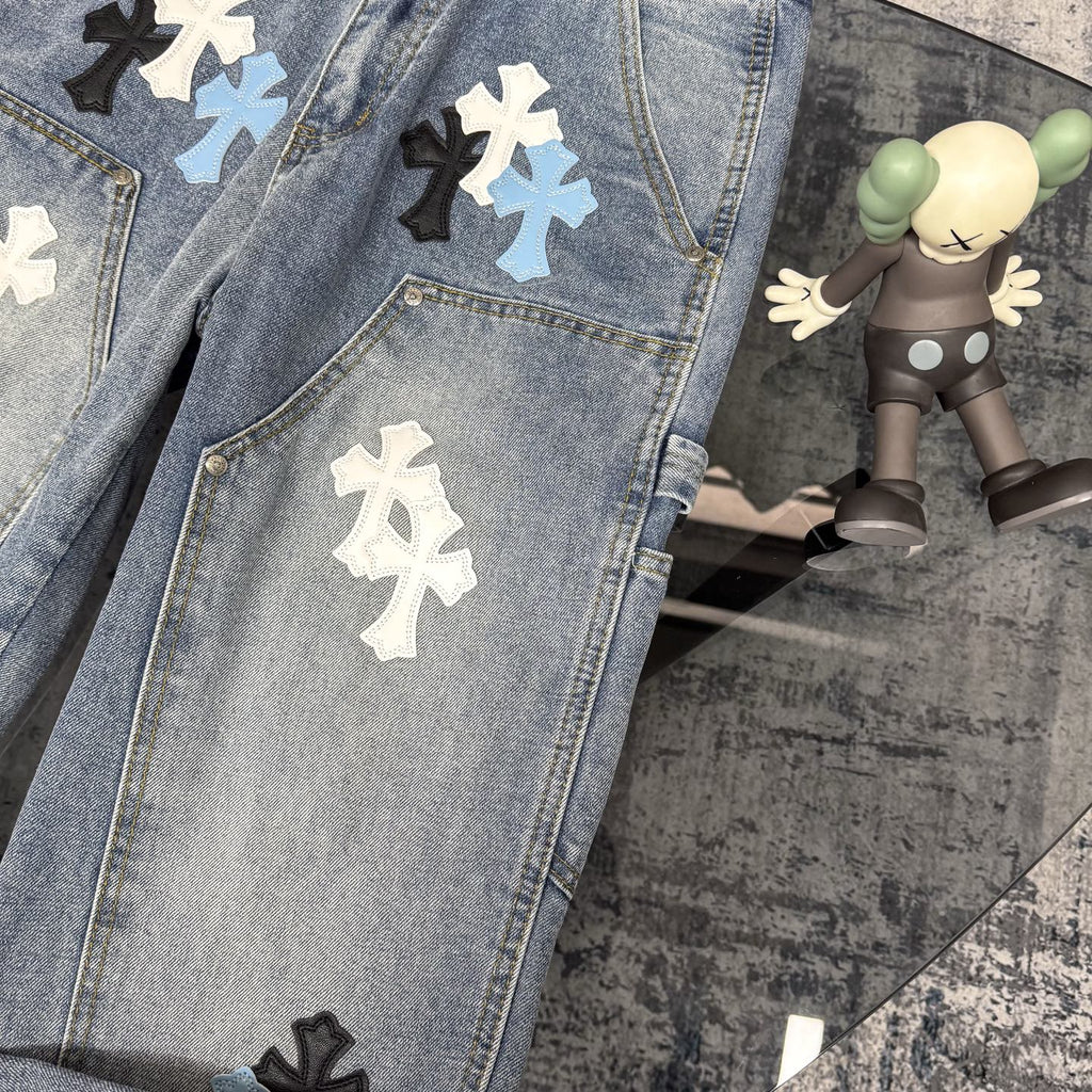 Light blue denim pants with cross applique patches across the legs