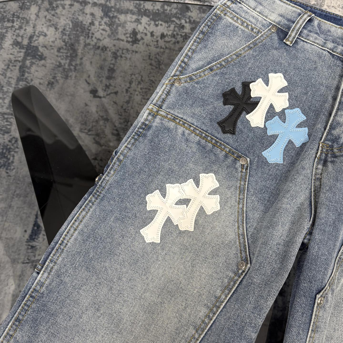 Light blue denim pants with cross applique patches on the front leg