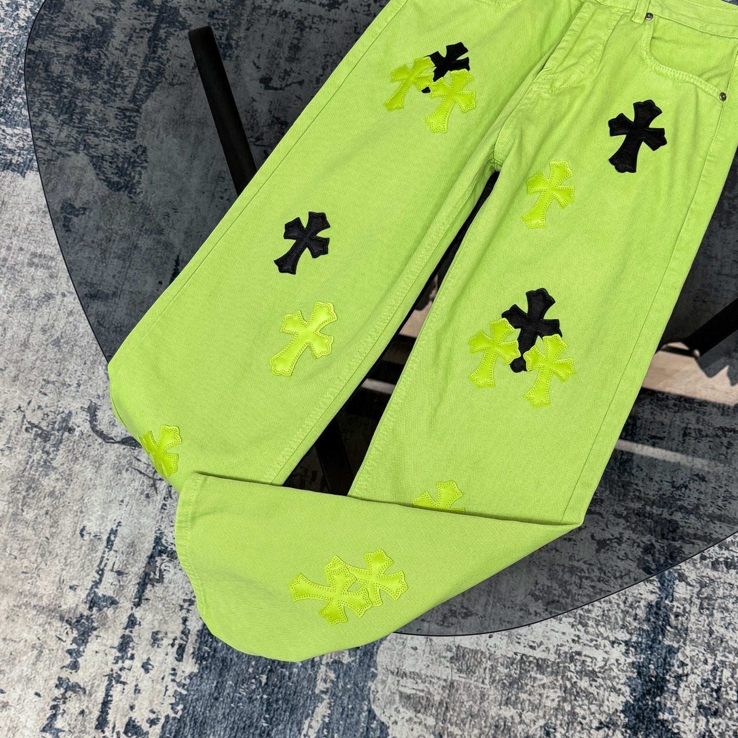 Neon lime green pants showing front cross applique print and button closure detail