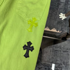 Lime green pants with front patch pocket and yellow and black cross appliques on leg