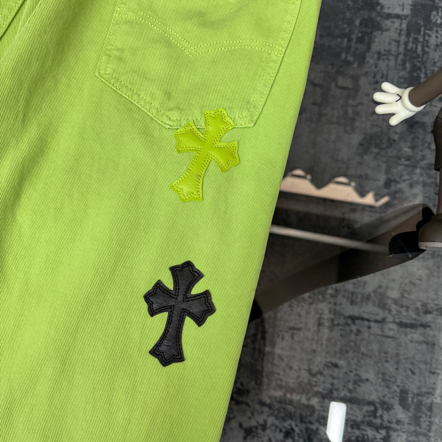 Lime green pants with front patch pocket and yellow and black cross appliques on leg