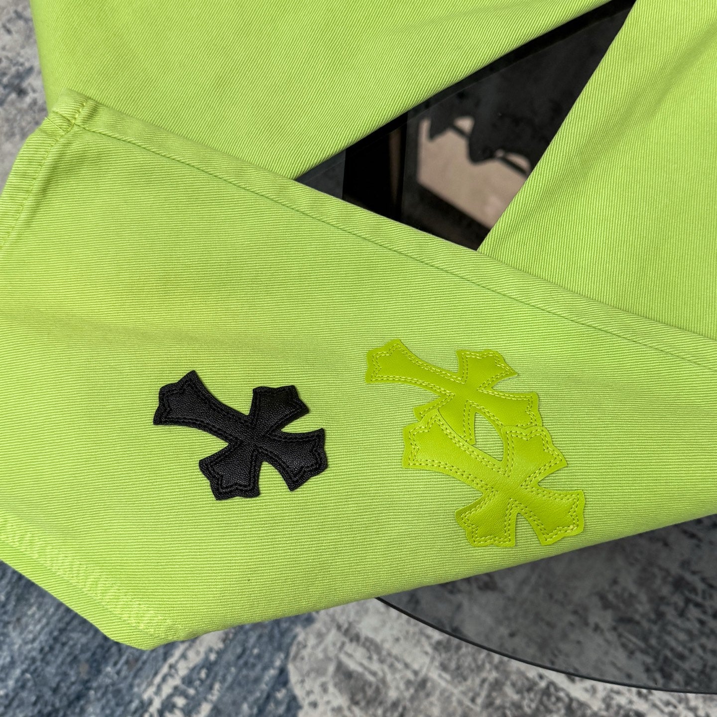Lime green pants with cross patches on the leg and arched pocket seam details
