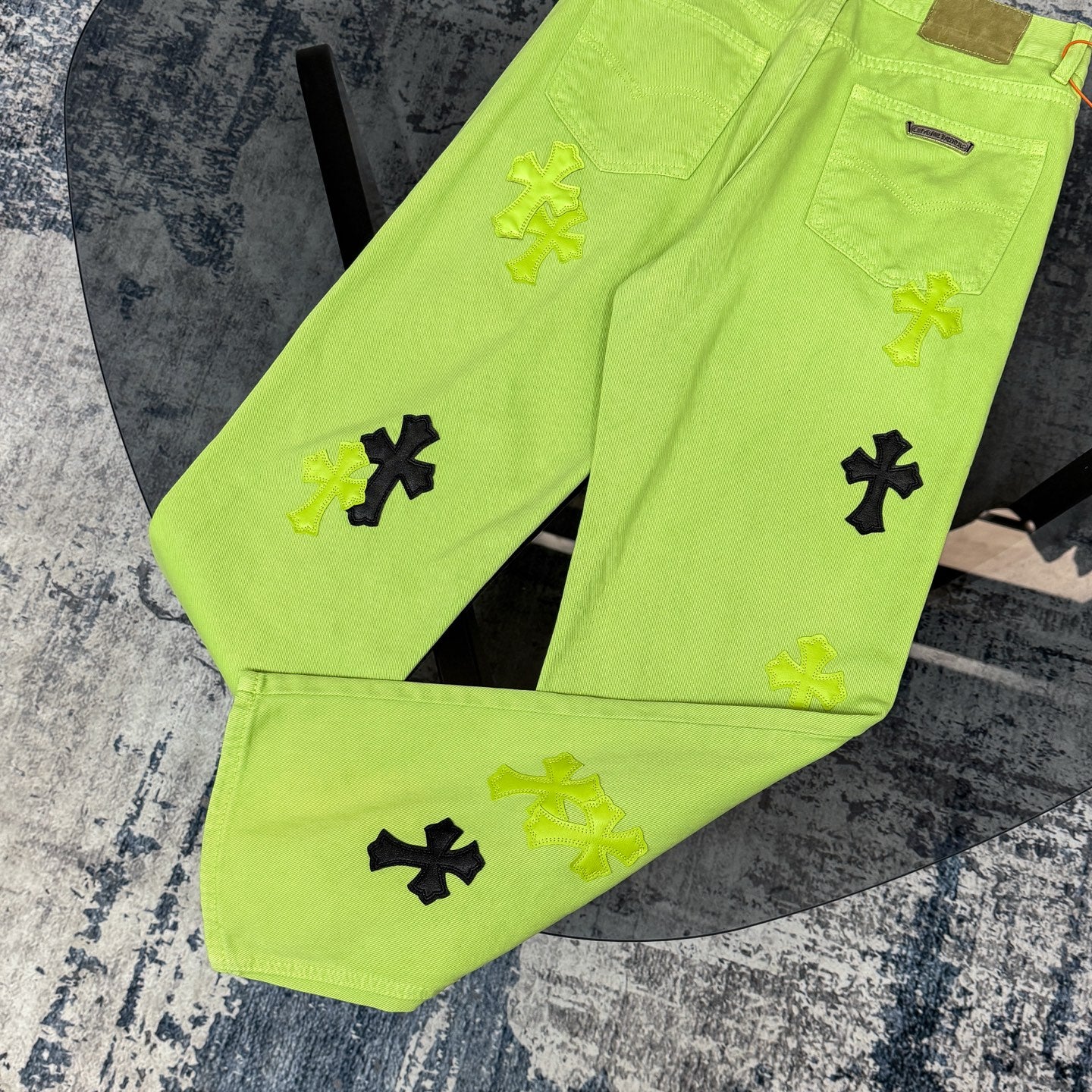 Lime green pants with black and yellow cross appliques across the front legs