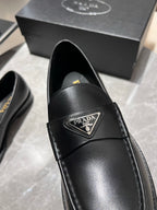 Black leather loafer upper close-up with Prada logo patch and stitching