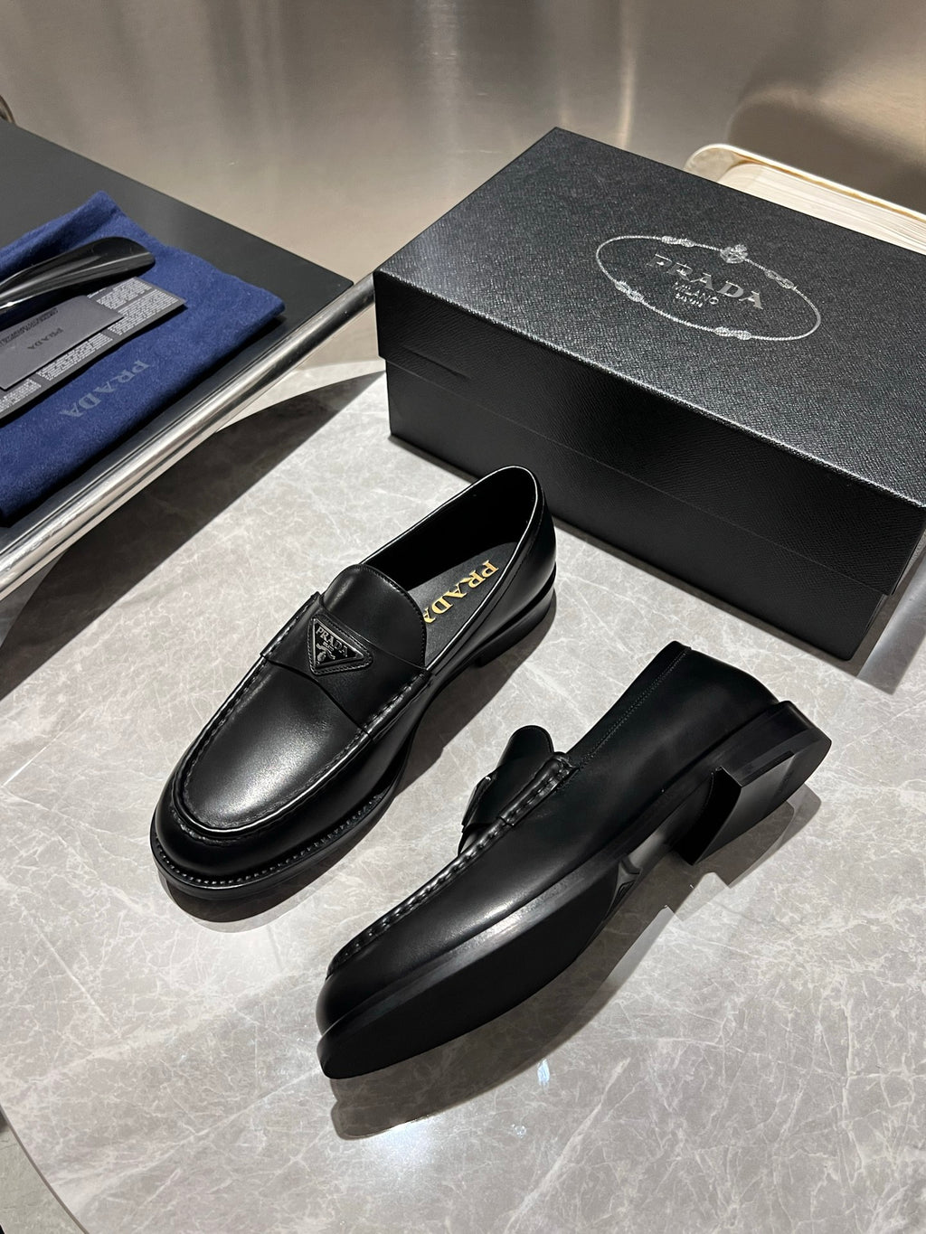 Black leather loafers with Prada logo, side view with visible stitching