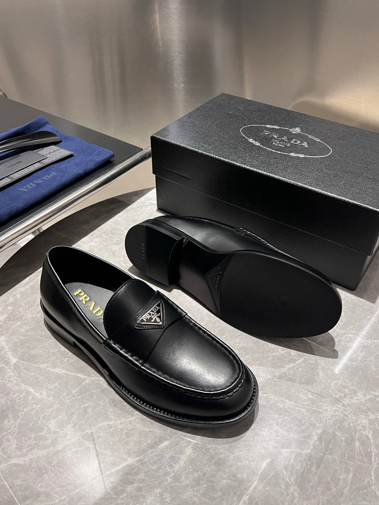 Black leather slip-on loafers with Prada logo patch and cushioned sole