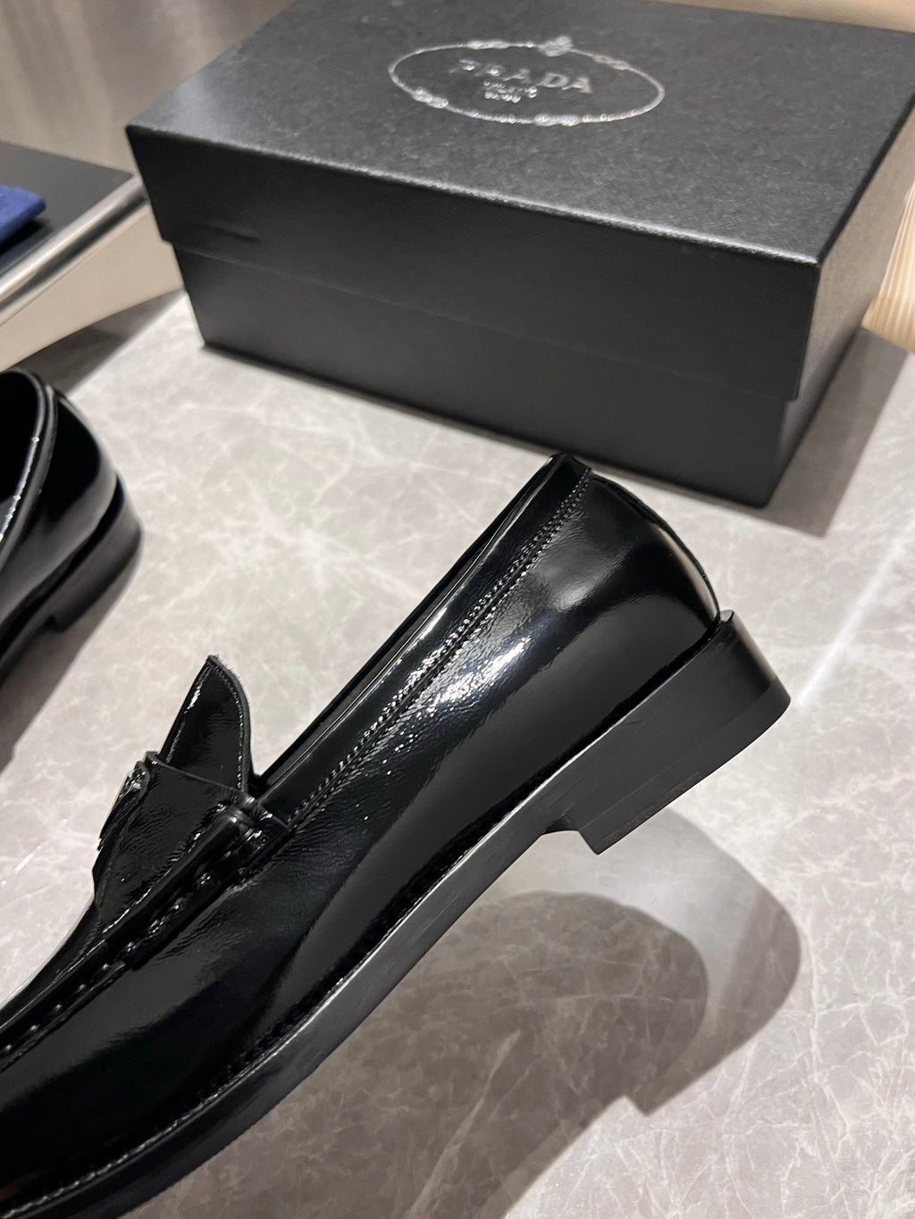 Prada unisex black patent loafer close side view with decorative stitching