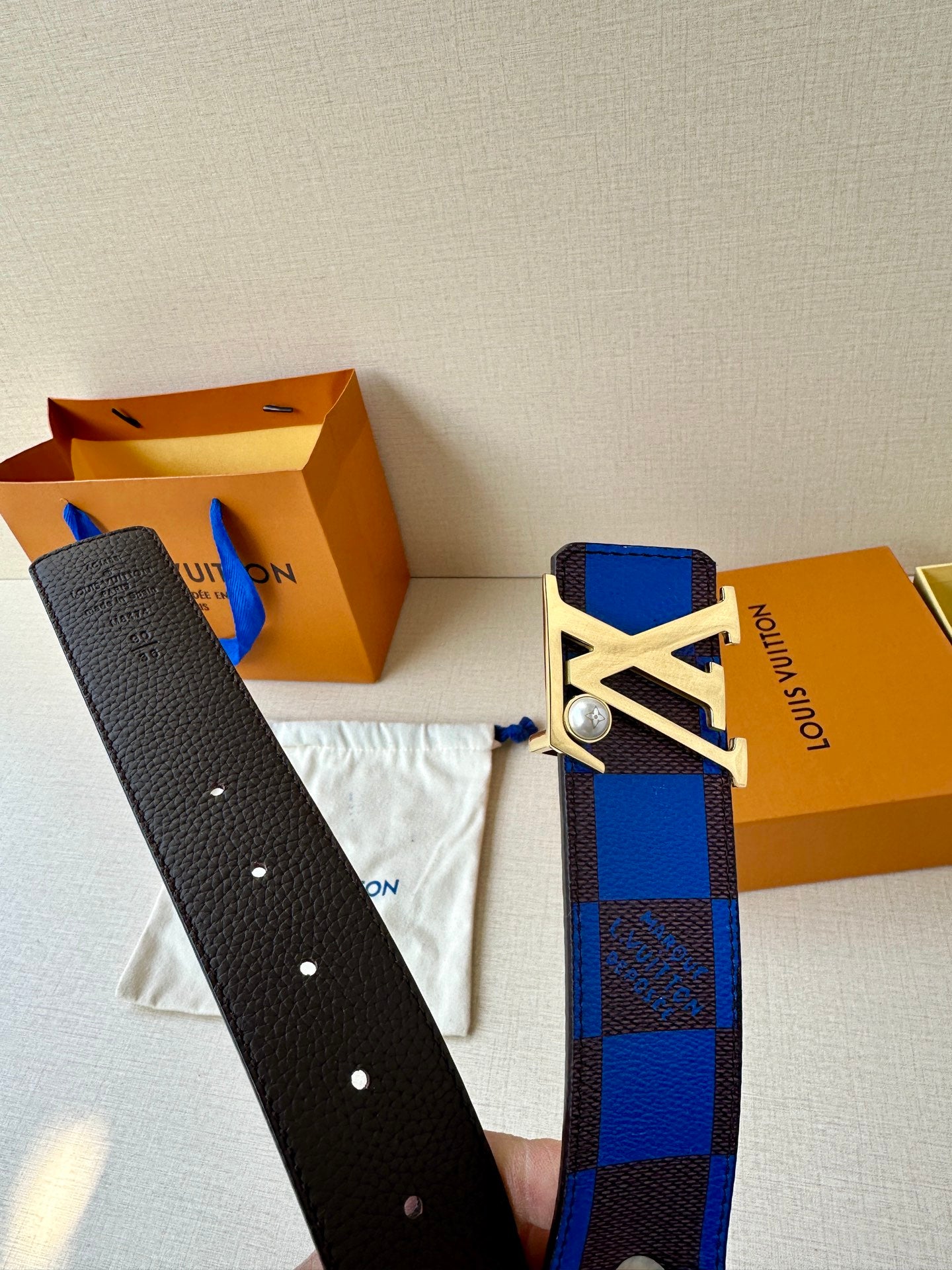 Louis Vuitton belt strap with punched holes and blue check panel with LV buckle.