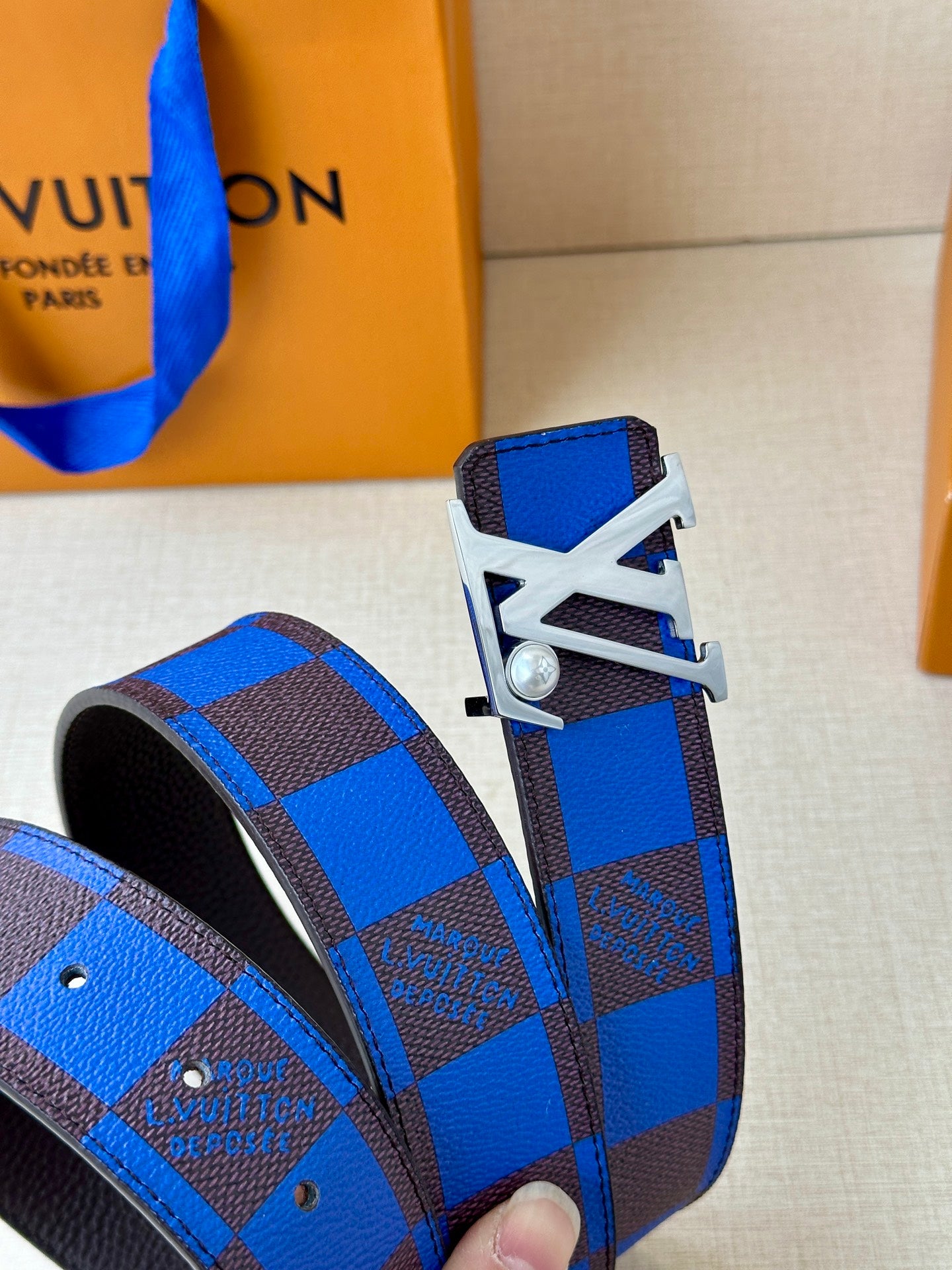 Louis Vuitton belt view of blue check strap ends with silver buckle hardware.