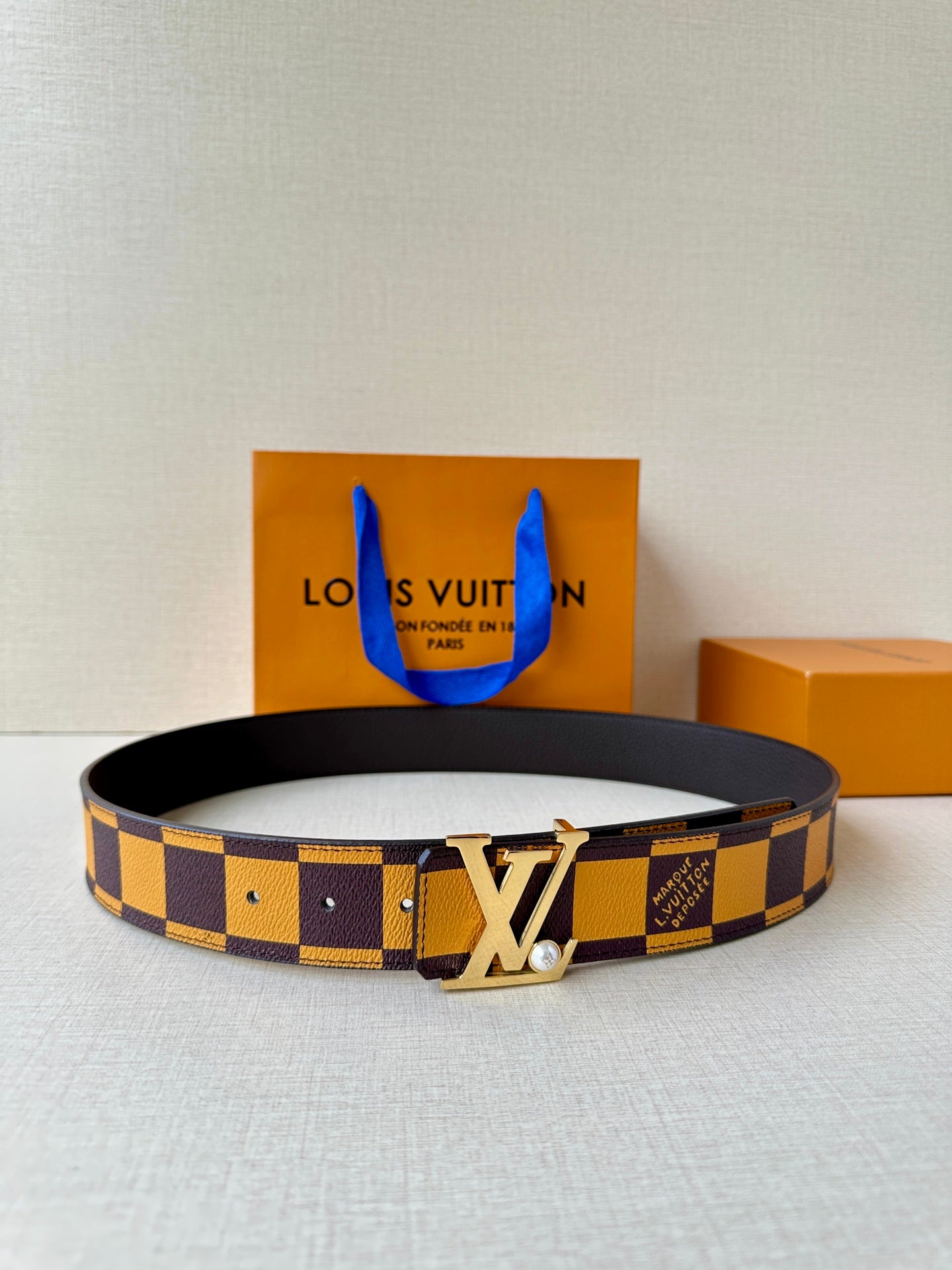 Check-pattern leather belt with dark strap and large gold-tone LV logo buckle
