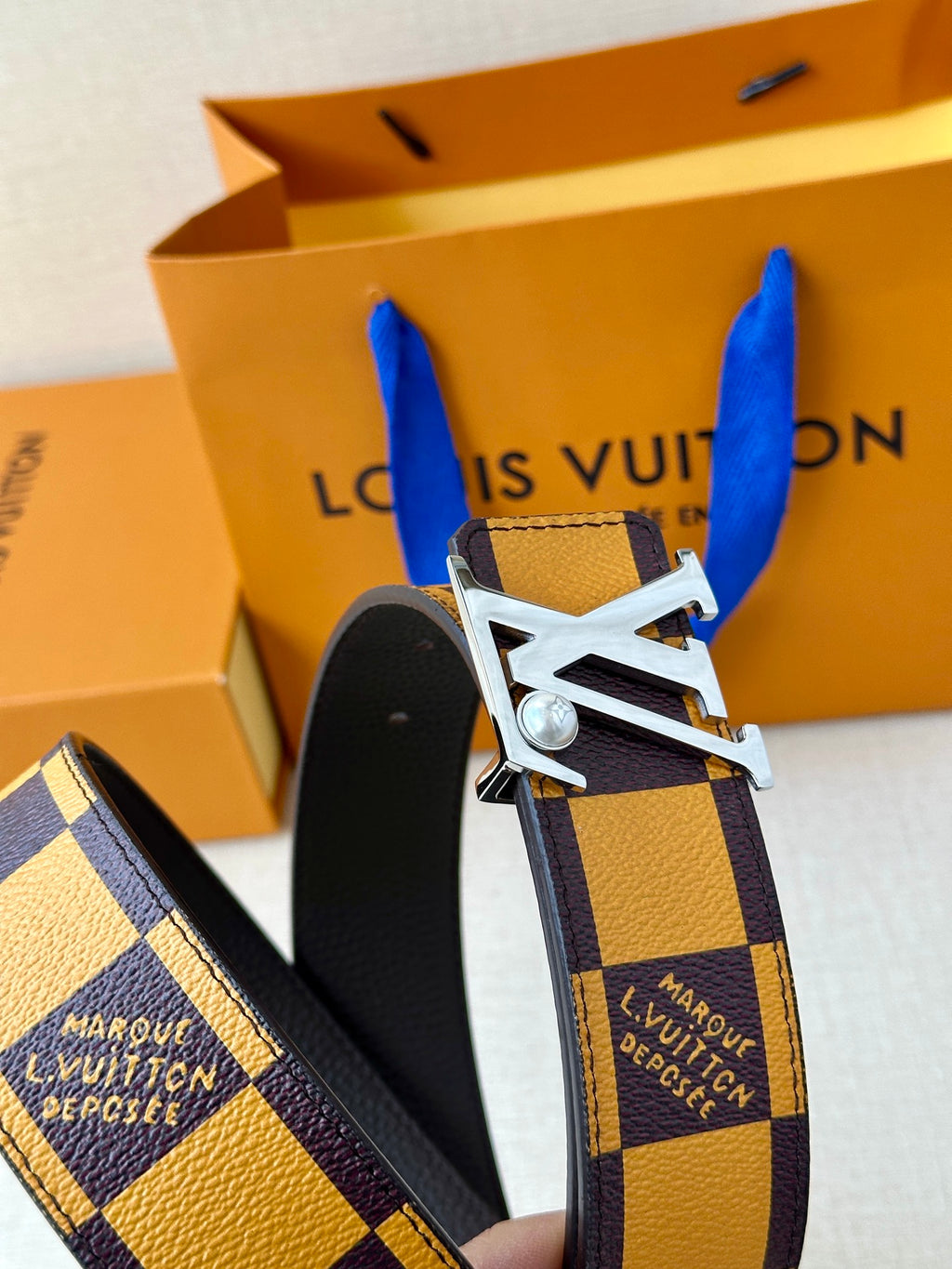 Check-pattern belt detail with silver-tone buckle and dark leather backing
