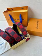 Louis Vuitton belt with red-and-black check strap and silver LV buckle, styled with pouch