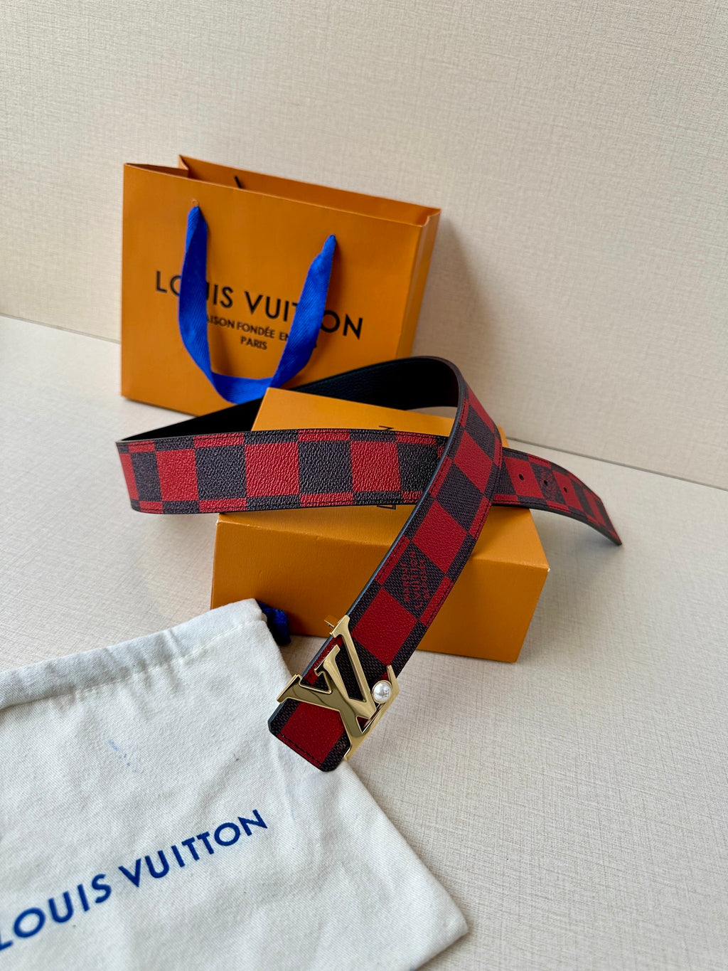 Louis Vuitton belt with red-and-black check strap, silver buckle, and attached end