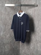 Navy polo shirt on hanger with white pointed collar and embroidered chest logo