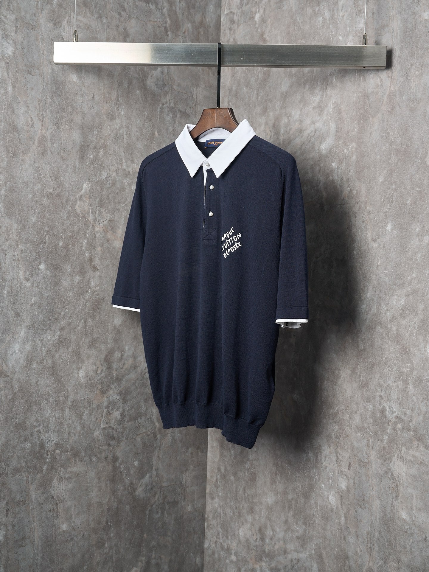 Navy polo shirt front with white collar, three-button placket, short sleeves.