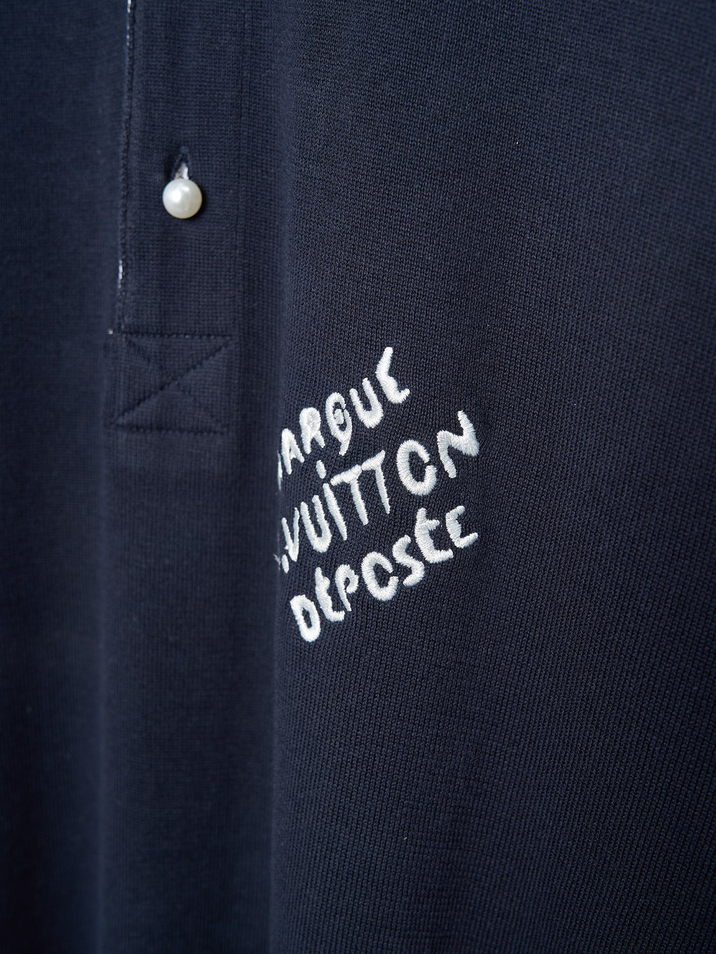 Navy polo shirt with embroidered script logo near the button placket