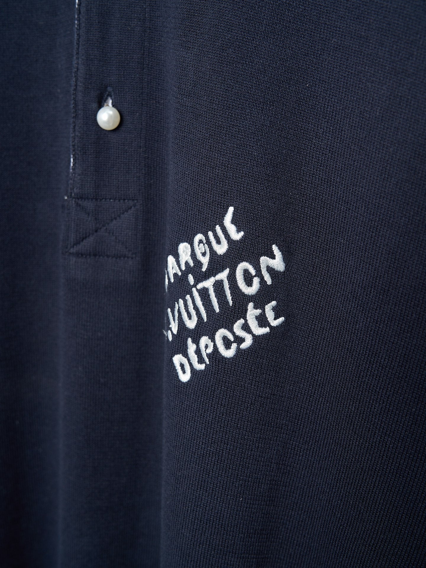 Navy polo shirt with embroidered script logo near the button placket